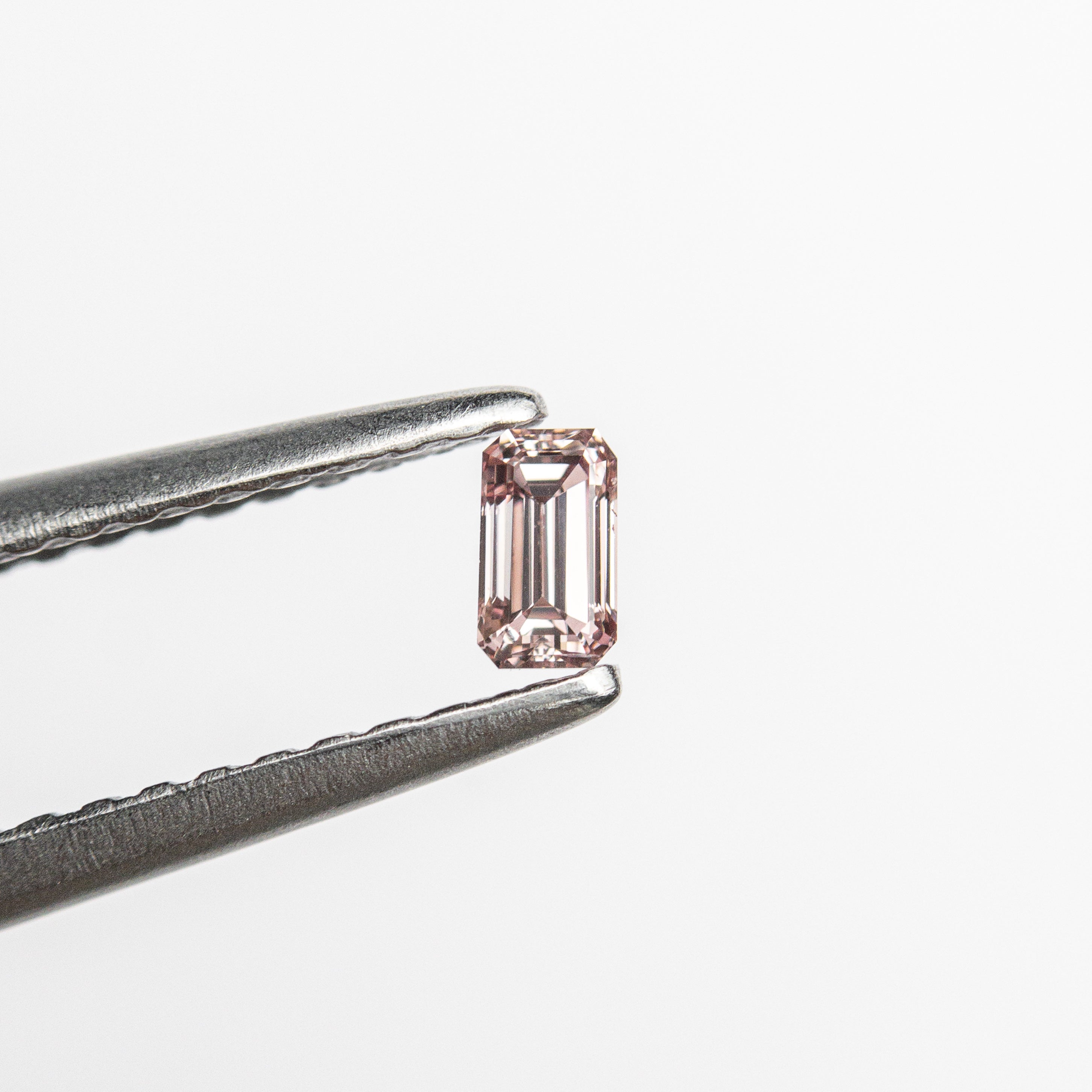 The 0.12ct 3.42x1.96x1.76mm VS1 Fancy Intense Orangy Pink Cut Corner Rectangle Step Cut 24108-01 by East London jeweller Rachel Boston | Discover our collections of unique and timeless engagement rings, wedding rings, and modern fine jewellery.