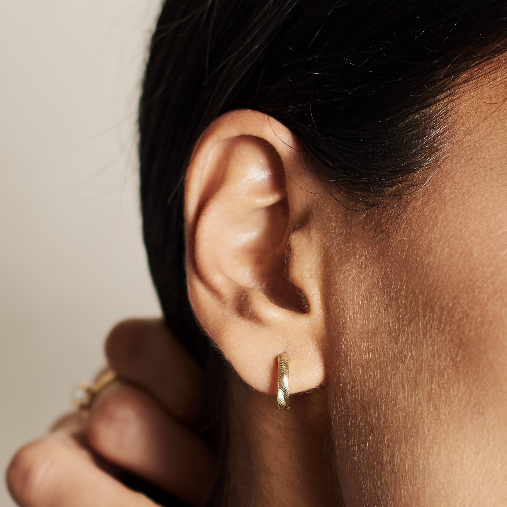 The 12.8mm Engraved Chevron Huggie Hoop Earrings by East London jeweller Rachel Boston | Discover our collections of unique and timeless engagement rings, wedding rings, and modern fine jewellery.