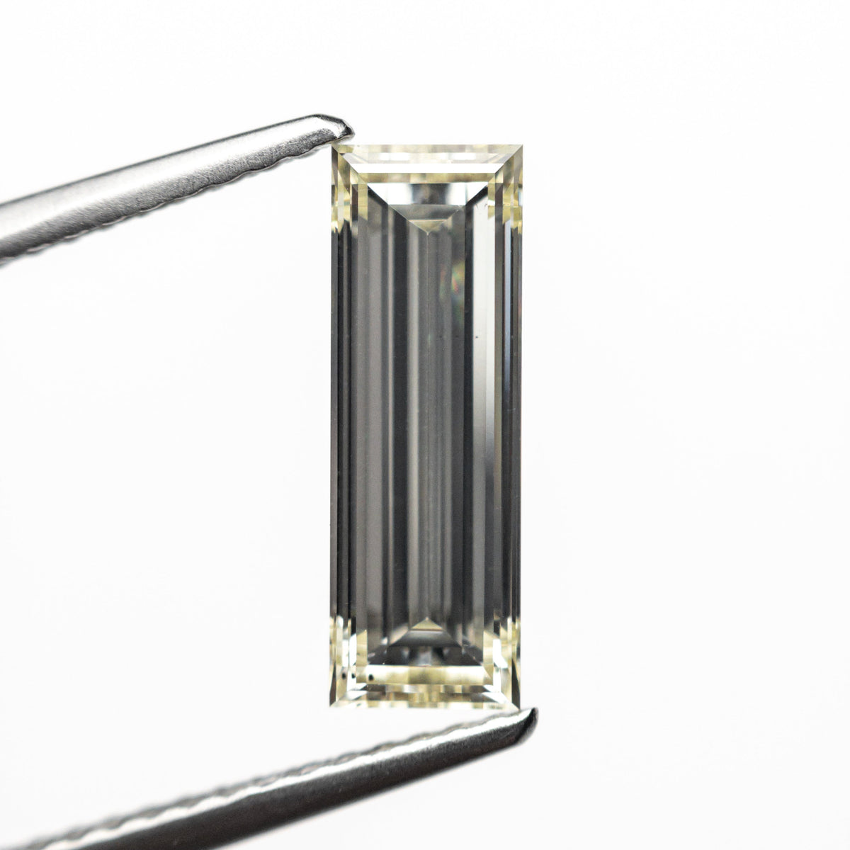 The 1.52ct 12.21x4.16x2.86mm VS2 O-P Baguette Step Cut 26124-01 by East London jeweller Rachel Boston | Discover our collections of unique and timeless engagement rings, wedding rings, and modern fine jewellery.