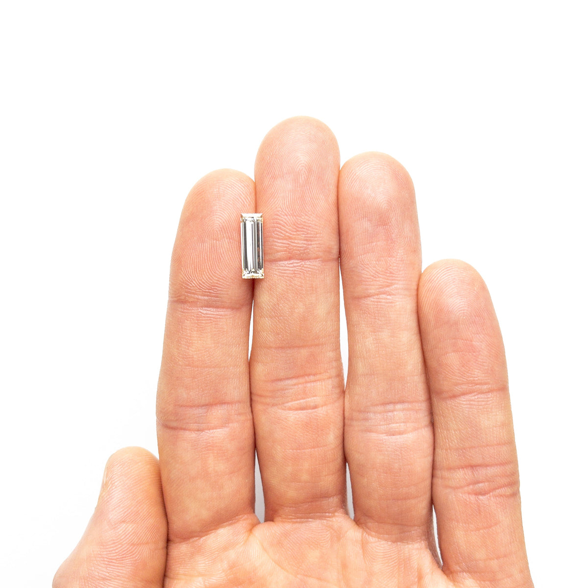 The 1.52ct 12.21x4.16x2.86mm VS2 O-P Baguette Step Cut 26124-01 by East London jeweller Rachel Boston | Discover our collections of unique and timeless engagement rings, wedding rings, and modern fine jewellery.